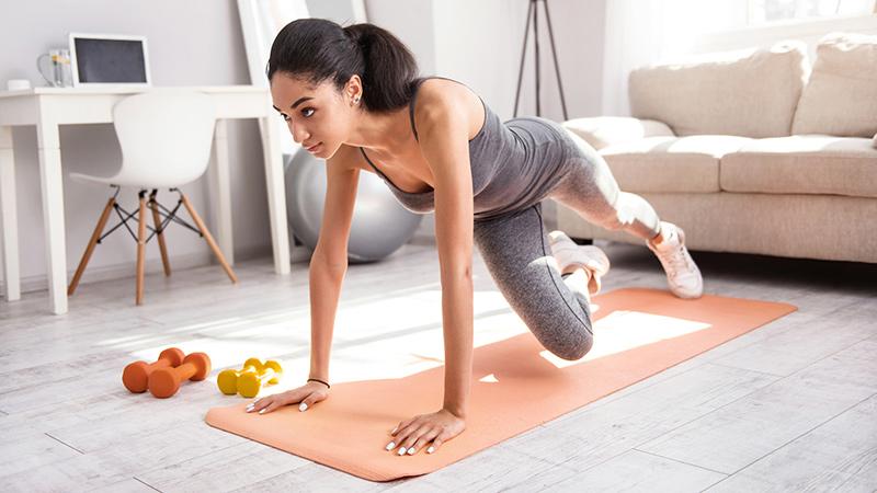 Woman doing yoga or pilates on mat in home